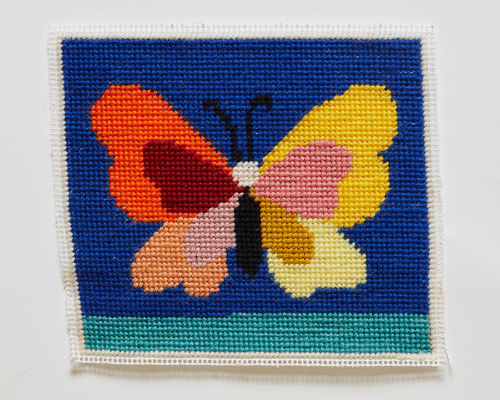 A photo of a woven piece of fabric with a butterfly on it.