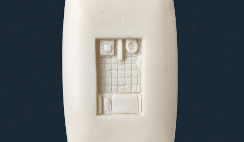 A photo of a bar of soap with a jail cell carved into it from a bird's eye view.