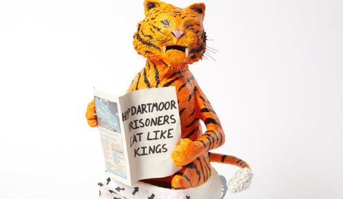 A sculpture of a tiger reading a newspaper.