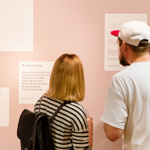 A photo of a couple looking at poems from a Koestler Arts exhibition.