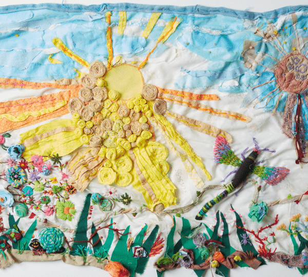 A multimedia painting with a sun on it made out of different textured materials.
