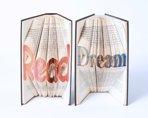 A photo of two books with Read and Dream carved out of their pages.