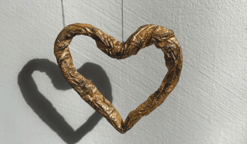A photo of a gold heart made out of tissue.