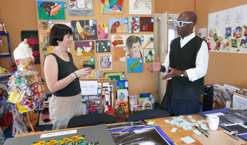 A photo of a man and a woman who are judges at The Koestler Awards, they're standing in a room full of art.
