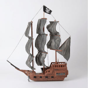 Woodcraft model of traditional ship with large grey sails and a black flag at the top.