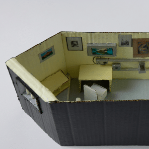 Sculpture made of cardboard depicting the inside of a prison cell.