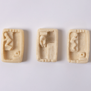 Three hand-carved prison-issue soaps depicting scenes from a day in a prison cell.