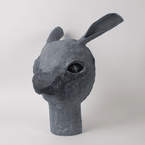Pale grey papier-mache rabbit head with cosmic design in eyes.